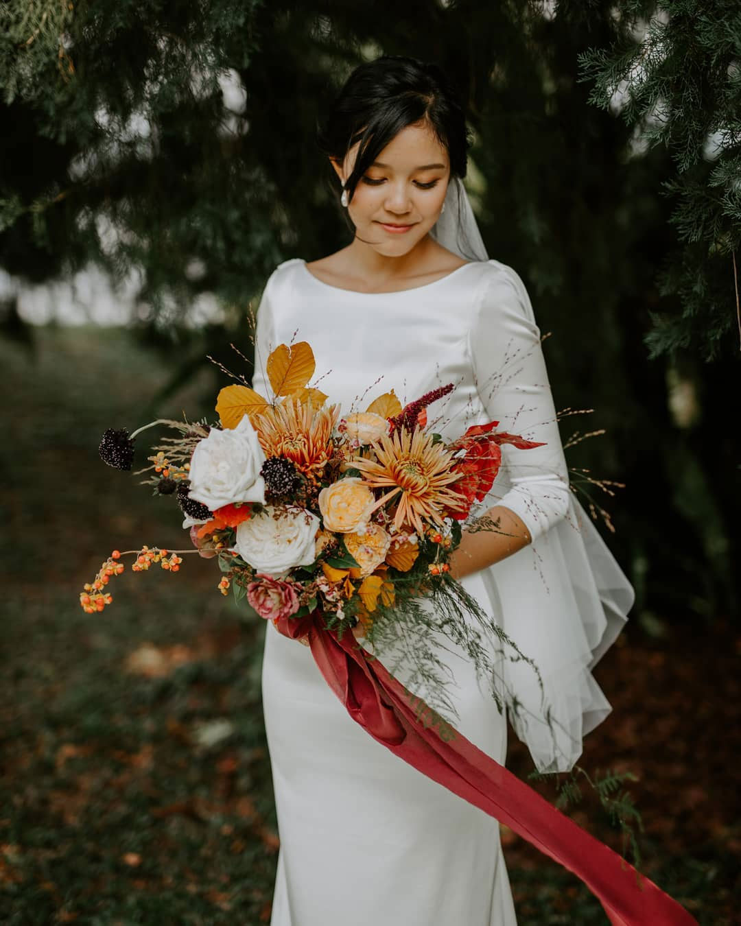 bride with fall bridal bouquet and red ribbon