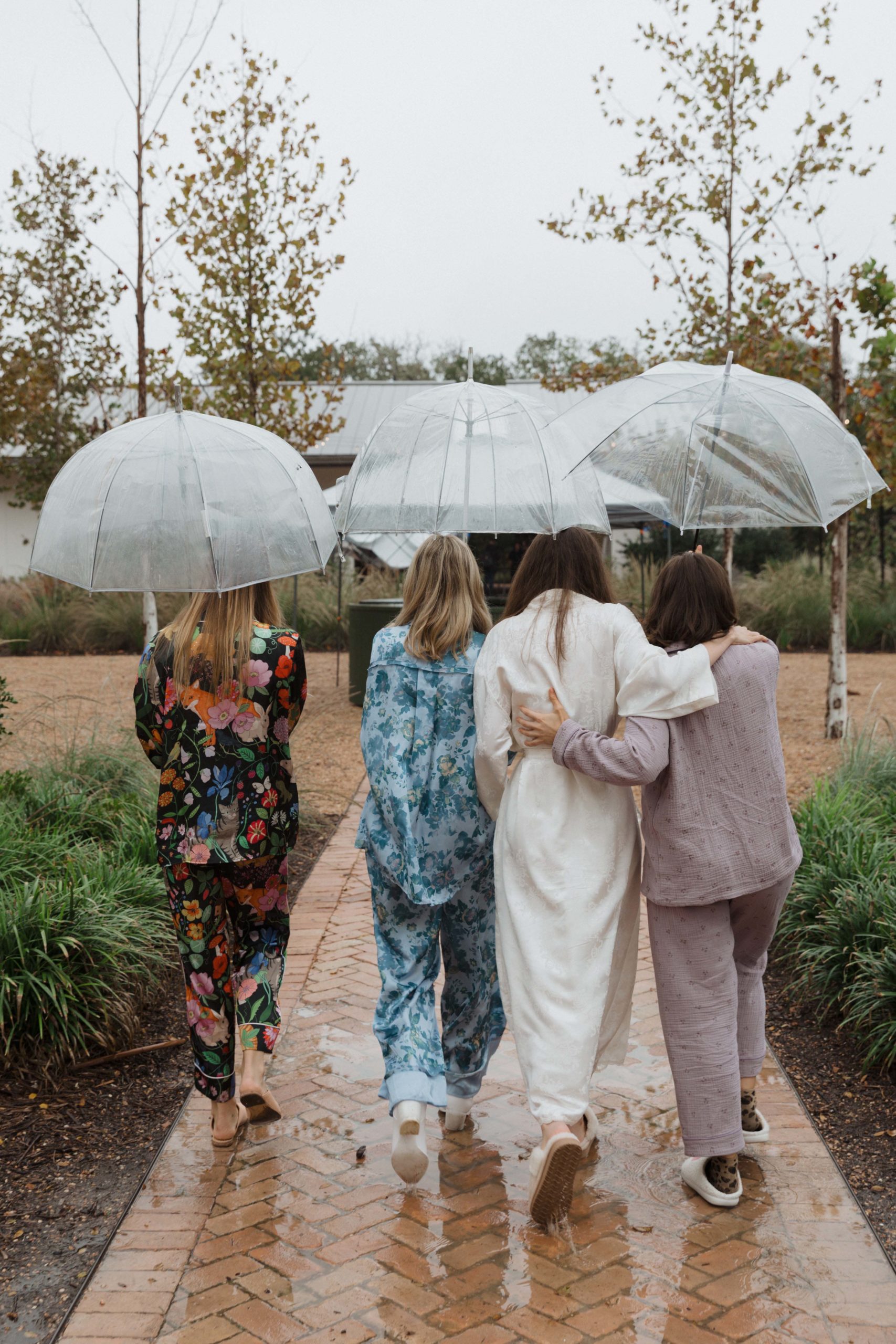 bridesmaids pjs with umbrellas on rainy day wedding