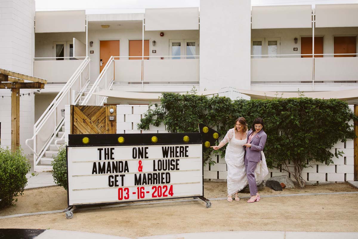 couple posing with ace hotel wedding sign