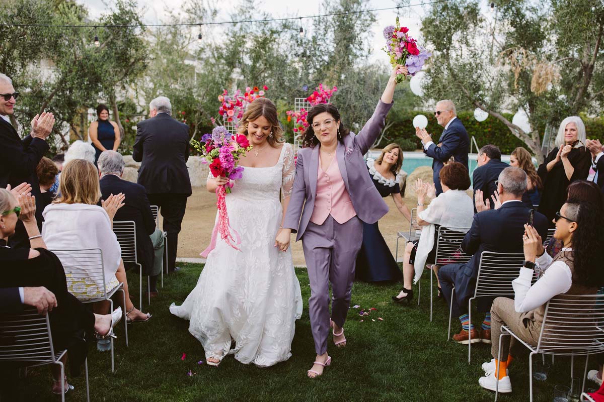 brides at wedding ceremony in lavender suit with hot pink flowers