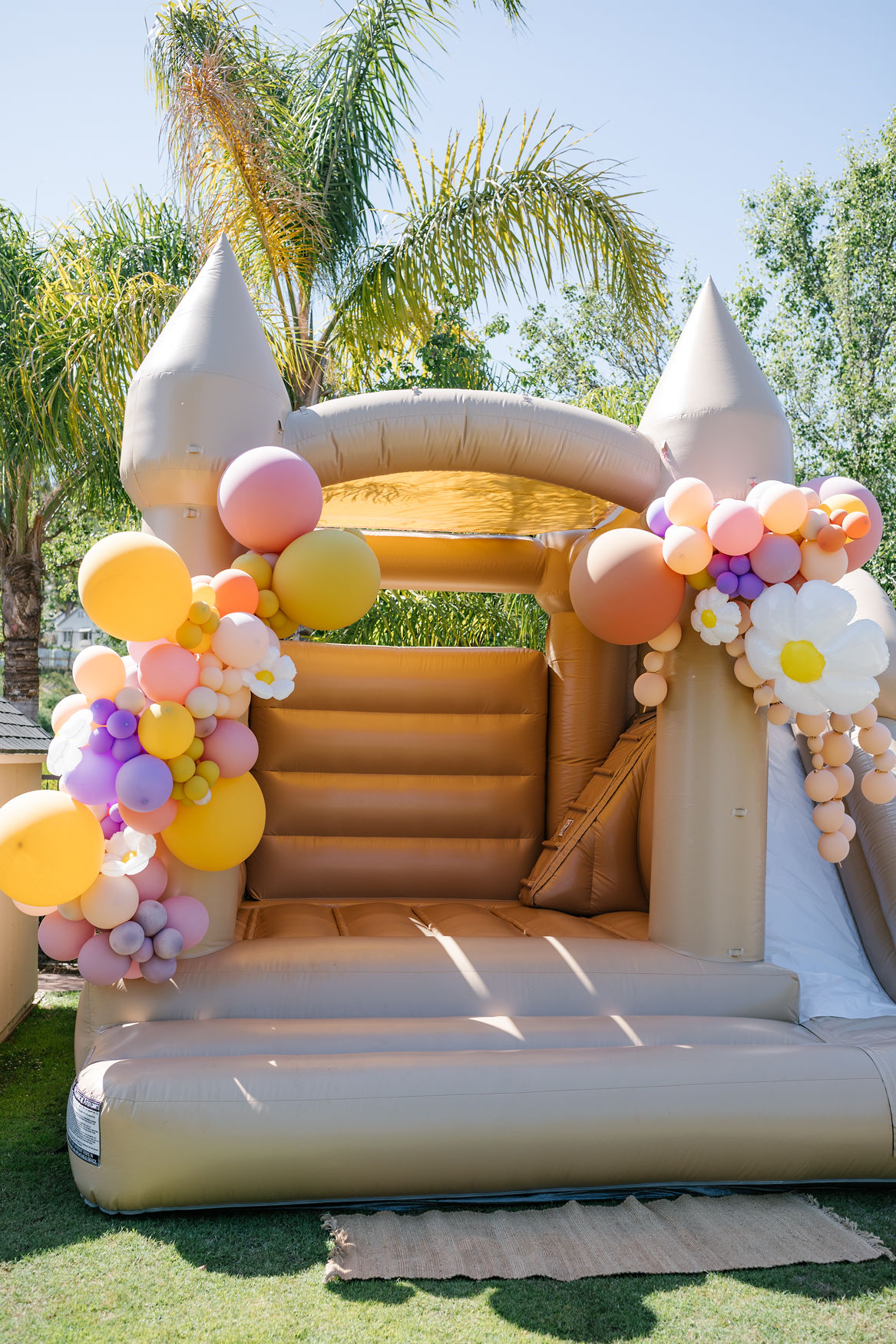 castle bounce house with pastel balloons and flowers