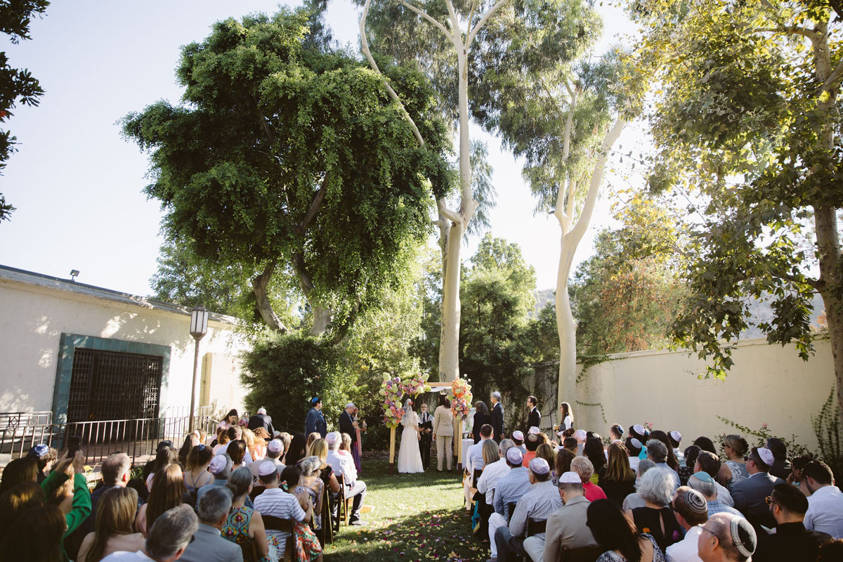 bride and groom with colorful floral chuppah at LA River Center wedding